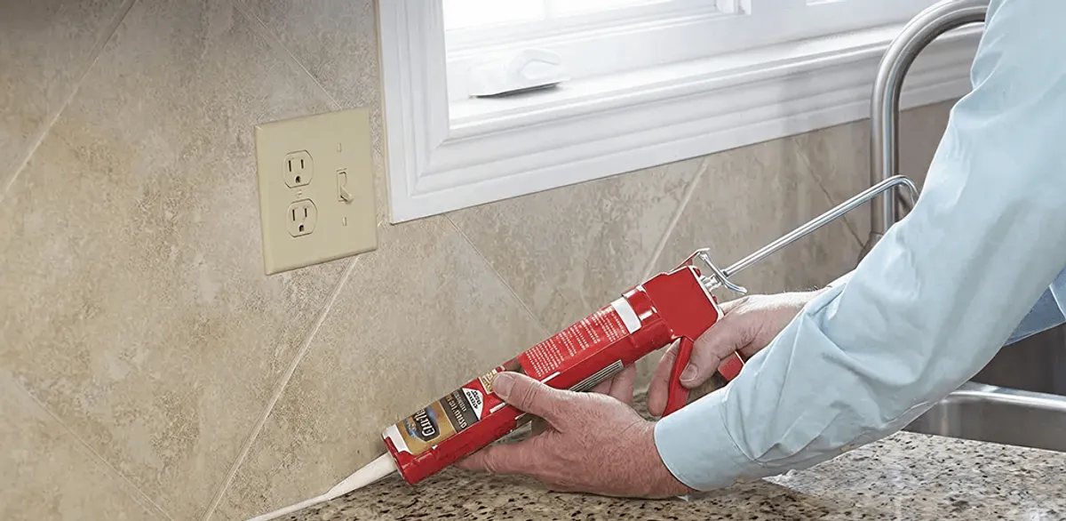 Handyman applying caulk along a kitchen backsplash and countertop seam in Sioux Falls, SD